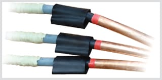 Three prepared cable cores in a row, each with a black stress control tube recovered over the step where the screen ends, red tubing continuing past it, and bare copper conductor at the end